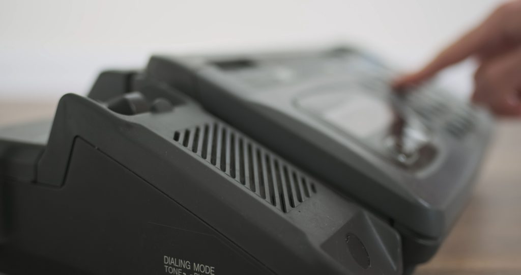 Man's hand picks up fax machine and dials number. Side view, close-up. High quality photo