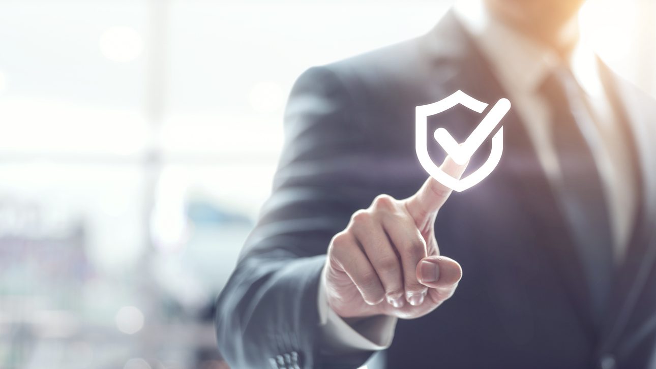 Technology computer and internet cyber security and anti virus concept, Businessman pressing security shield with check mark icon with blurred office background.