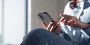 Young woman using mobile phone for online shopping via mobile app at home. Casual business woman surfing the internet on smartphone during working from home, close up