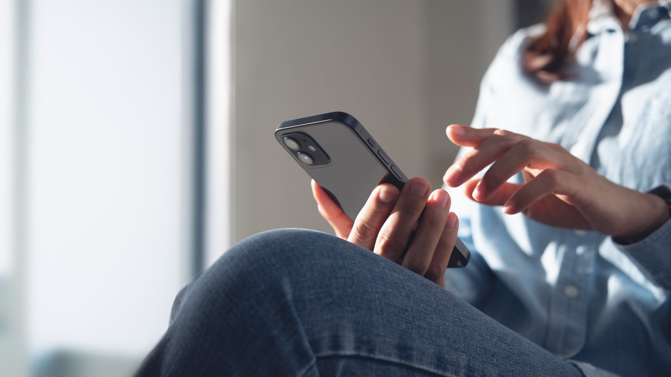 Young woman using mobile phone for online shopping via mobile app at home. Casual business woman surfing the internet on smartphone during working from home, close up