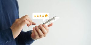 close up on customer man hand pressing on smartphone screen with five star rating feedback icon and press level good rank for giving best score point to review the service , technology business concept