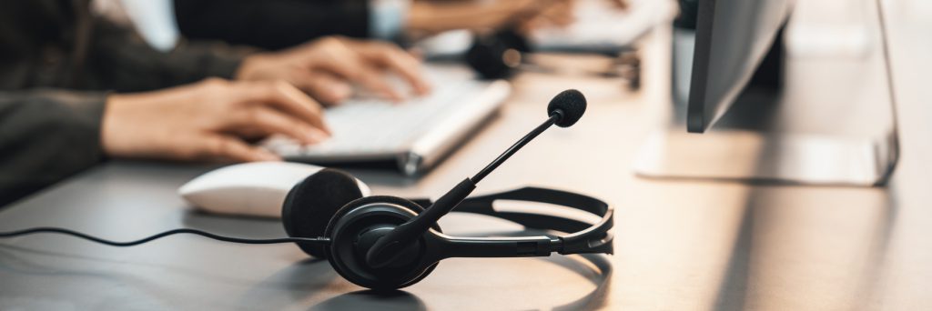 Panorama focus headset on call center workspace desk with blur background of operator team or telesales representative engage in providing client with customer support service or making sales. Prodigy